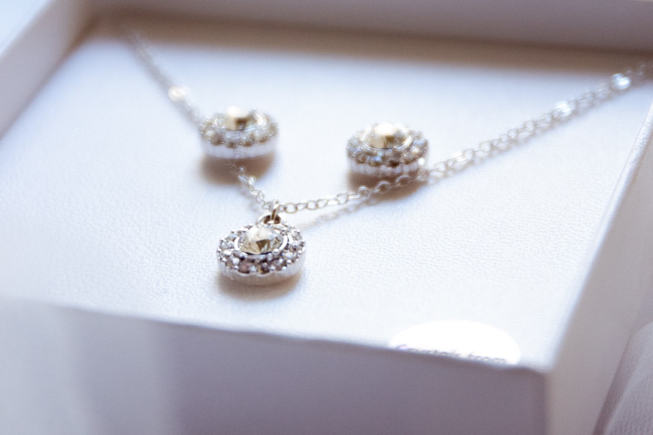 a white jewelry gift box holding a white gold gemstone necklace and matching studs