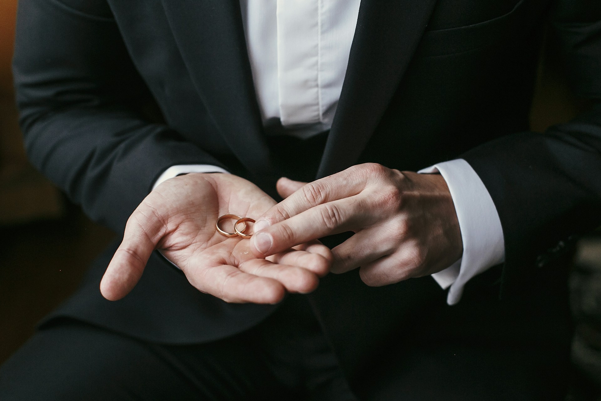 a man in a tuxedo holding two wedding bands